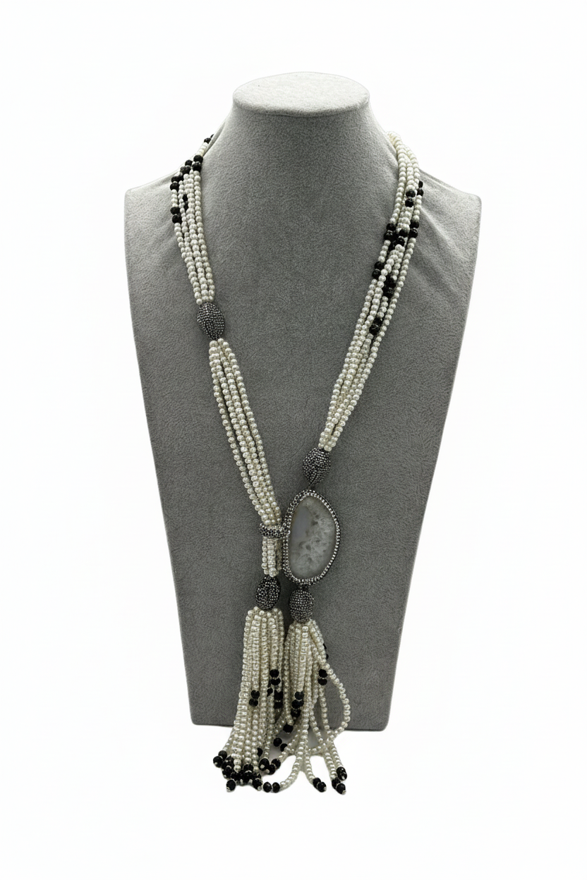 Beyaz arka plan üzerinde beyaz boncuk siyah boncuk aksamlı markazit oval sarkıtlı püsküllü uzun kolye