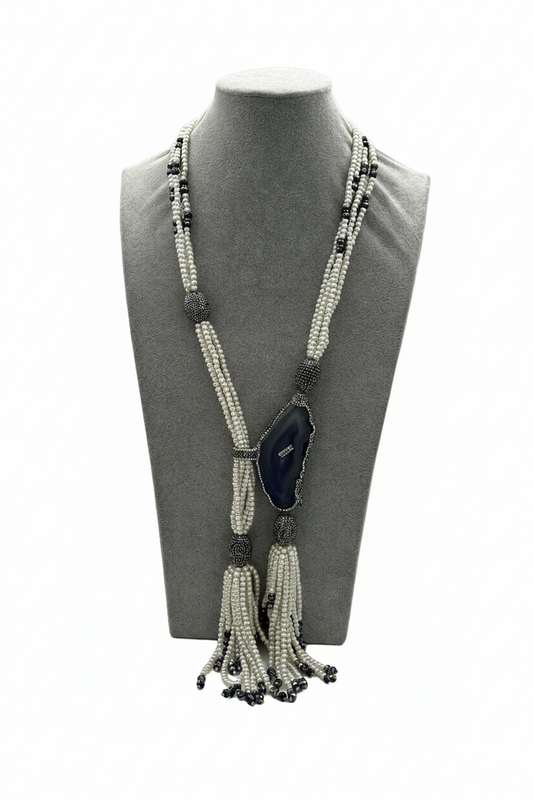 Beyaz arka plan üzerinde beyaz boncuk siyah akik markazit taşlı püsküllü uzun kolye