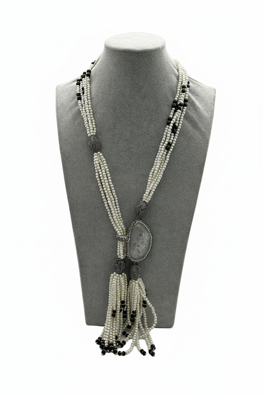 Beyaz arka plan üzerinde beyaz boncuk siyah boncuk aksamlı markazit oval sarkıtlı püsküllü uzun kolye