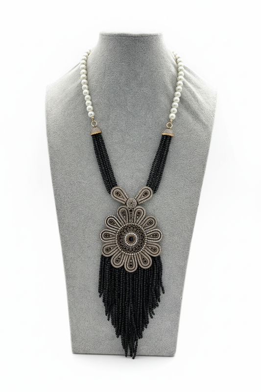 Beyaz arka plan üzerinde inci ve siyah boncuklu bronz çiçek pandantifli püsküllü kolye
