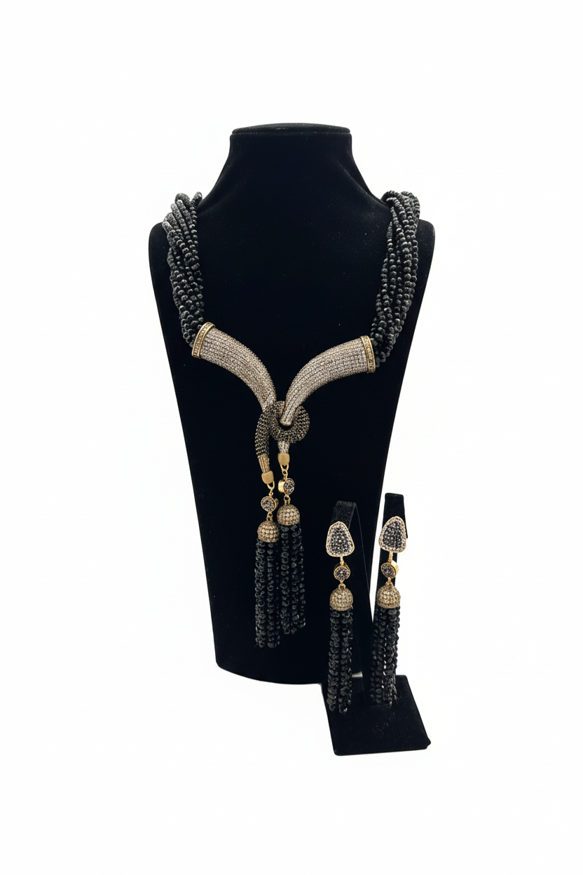 Beyaz arka plan üzerinde siyah boncuk zirkon taşlı bronz lariat kolye ve küpe seti