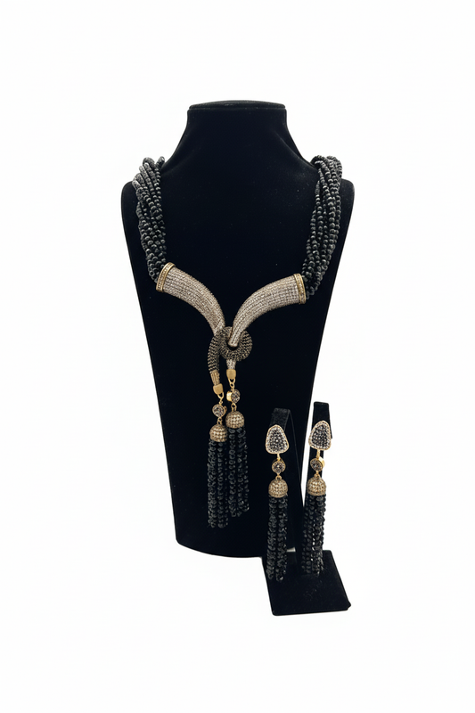 Beyaz arka plan üzerinde siyah boncuk zirkon taşlı bronz lariat kolye ve küpe seti